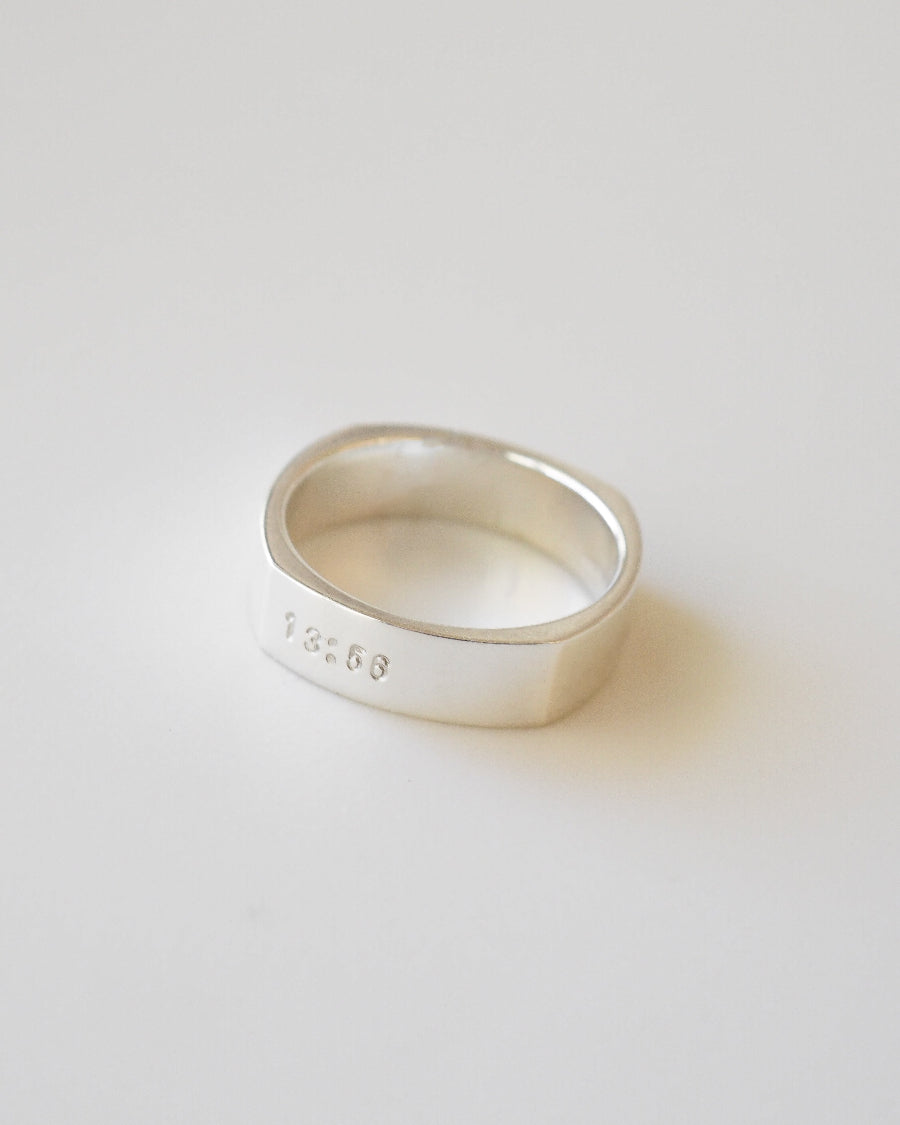 Silver ring with engraved text on a light gray background