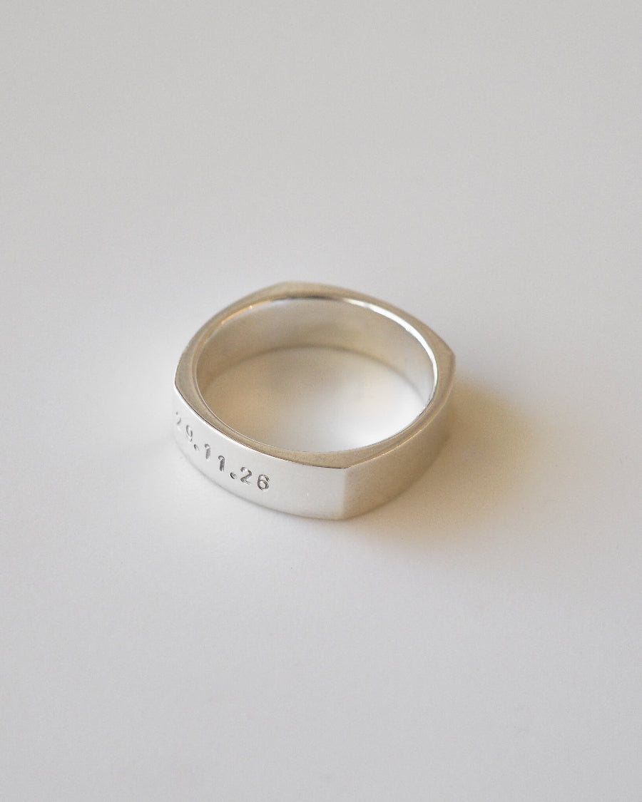 Silver ring with engraved text on a light gray background
