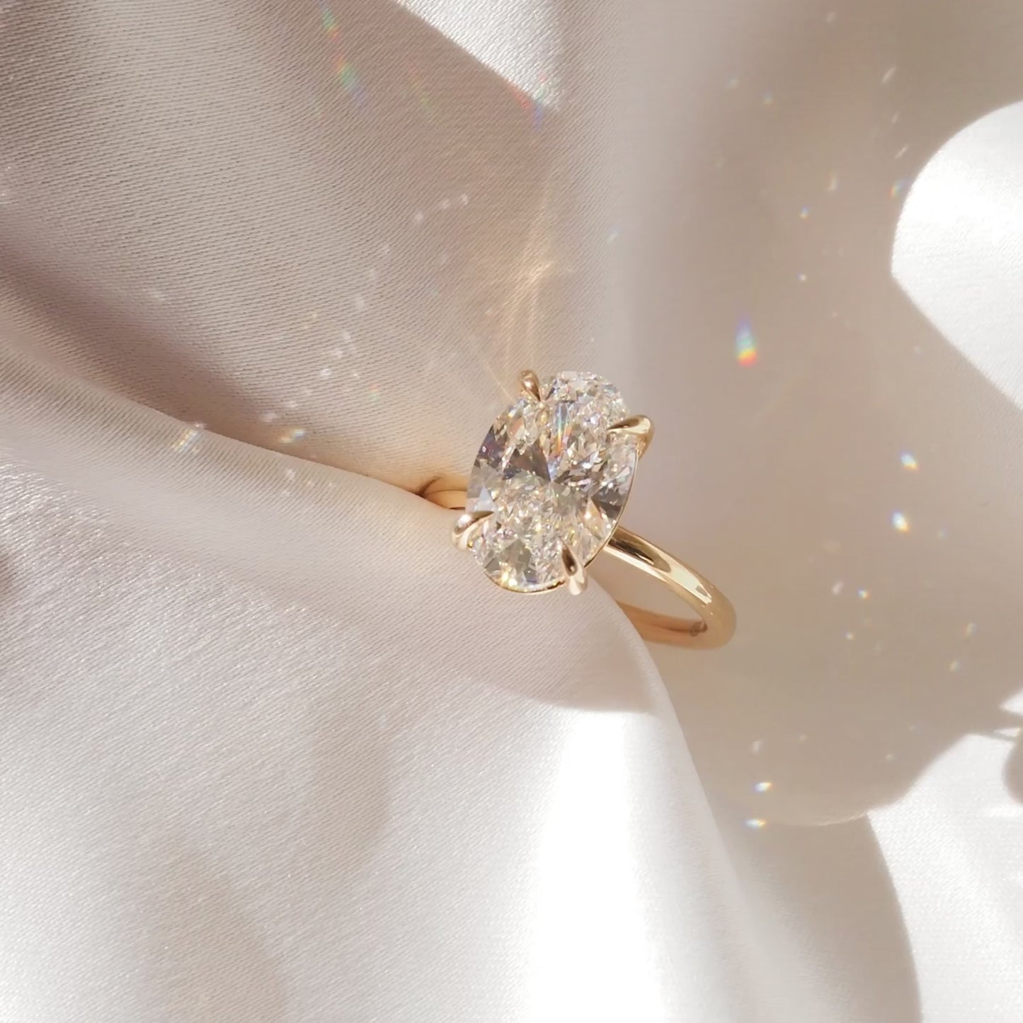Gold ring with a large, sparkling oval diamond displayed in an open white jewellery box, featuring the brand "Kate & Kole".