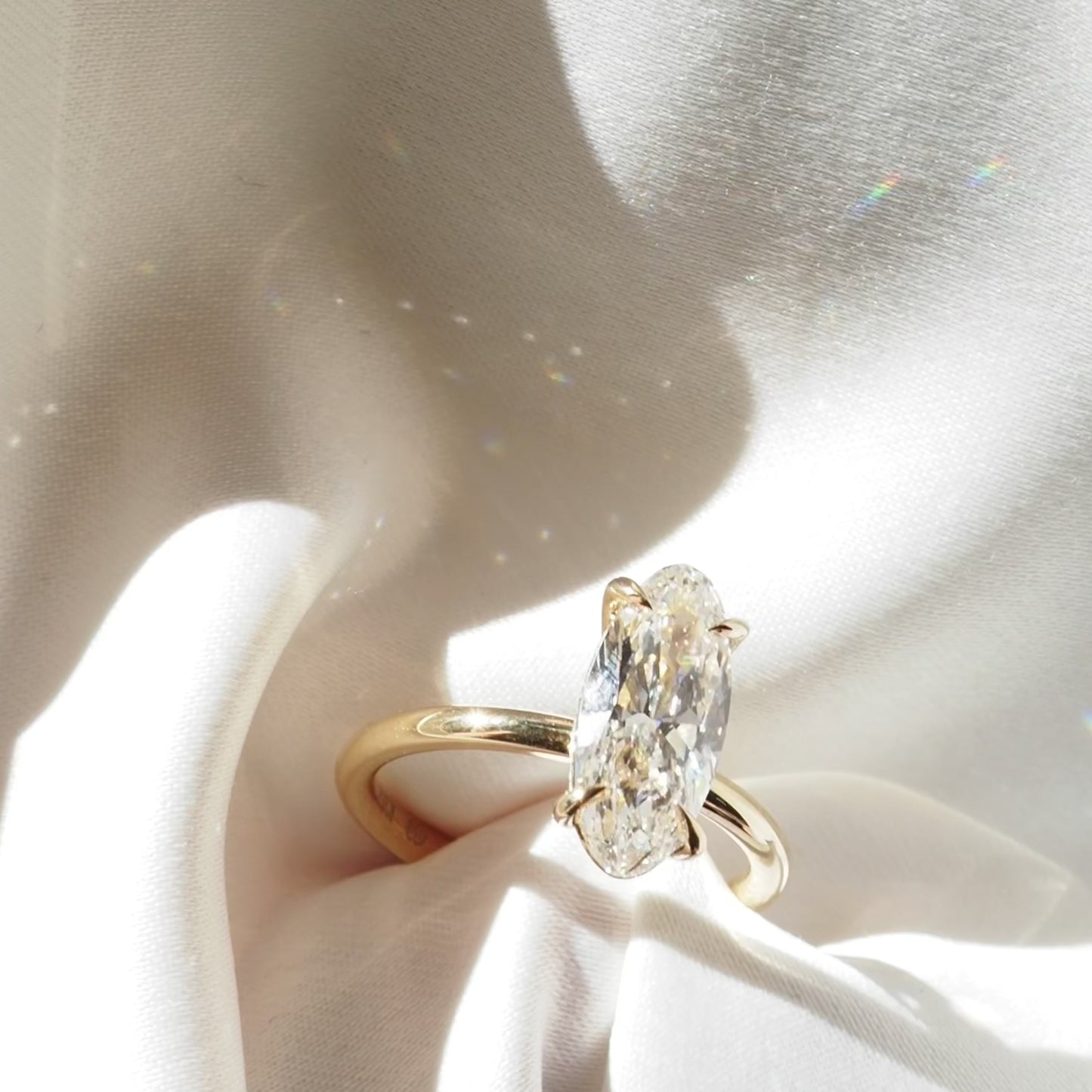 Gold ring with a Moval diamond on a light background